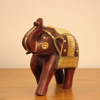 Elephant Showpiece with Brass Art Styled on Table Burgundy wooden elephant showpiece with brass art placed on a wooden table as a shelf or console accent.