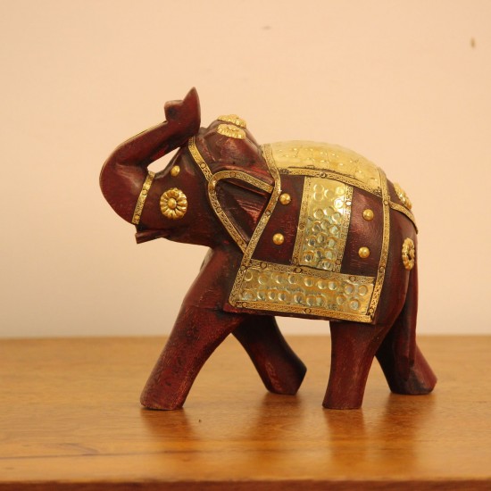 Elephant Showpiece with Brass Art Styled on Table Burgundy wooden elephant showpiece with brass art placed on a wooden table as a shelf or console accent.