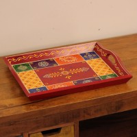 Hand Painted Red Patchwork Tray – Medium Medium wooden serving tray in red, hand painted in a colourful patchwork pattern of floral and geometric motifs in green, blue, and yellow, with cut-out side handles.
