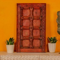 Handcrafted rustic red wooden door wall panel with intricate carvings and antique metal studs for traditional Indian wall decor