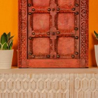 Handcrafted rustic red wooden door wall panel with intricate carvings and antique metal studs for traditional Indian wall decor