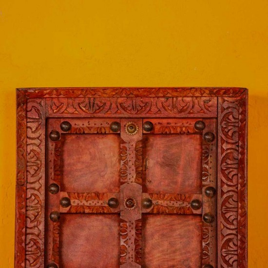 Handcrafted rustic red wooden door wall panel with intricate carvings and antique metal studs for traditional Indian wall decor