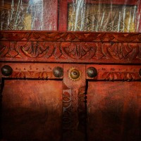 Handcrafted rustic red wooden door wall panel with intricate carvings and antique metal studs for traditional Indian wall decor