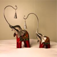 Handcrafted wood and metal painted elephant figurine set with trunk bells – decorative Indian handicraft on soft fabric background