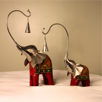 Handcrafted wood and metal painted elephant figurine set with trunk bells – decorative Indian handicraft on soft fabric background