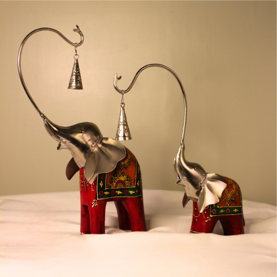 Handcrafted wood and metal painted elephant figurine set with trunk bells – decorative Indian handicraft on soft fabric background