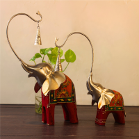 Handcrafted wood and metal painted elephant figurine set with trunk bells – decorative Indian handicraft on soft fabric background
