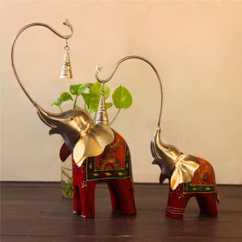 Handcrafted wood and metal painted elephant figurine set with trunk bells – decorative Indian handicraft on soft fabric background