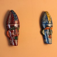 Hand-carved wooden tribal face mask hand painted in blue with a mustard-yellow crown, red eyes and lips, and fine white floral detailing across the face.