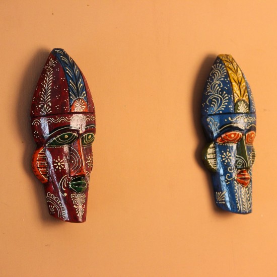Hand-carved wooden tribal face mask hand painted in blue with a mustard-yellow crown, red eyes and lips, and fine white floral detailing across the face.