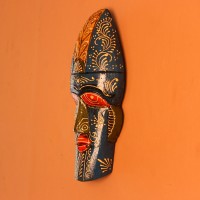 Hand-carved wooden tribal face mask hand painted in blue with a mustard-yellow crown, red eyes and lips, and fine white floral detailing across the face.