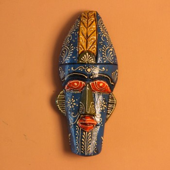 Hand-carved wooden tribal face mask hand painted in blue with a mustard-yellow crown, red eyes and lips, and fine white floral detailing across the face.