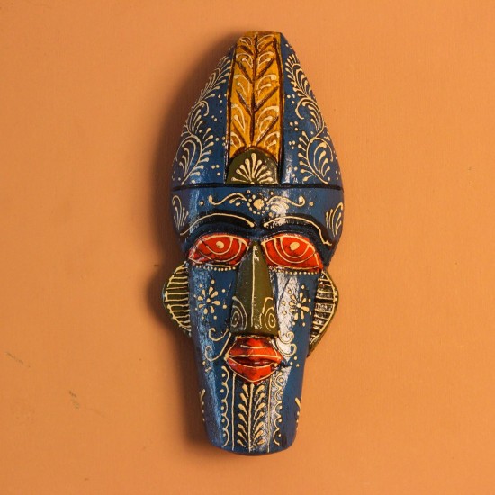 Hand-carved wooden tribal face mask hand painted in blue with a mustard-yellow crown, red eyes and lips, and fine white floral detailing across the face.