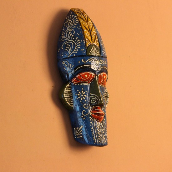 Hand-carved wooden tribal face mask hand painted in blue with a mustard-yellow crown, red eyes and lips, and fine white floral detailing across the face.