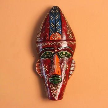 Hand-carved wooden tribal face mask hand painted in deep maroon with green eyes and lips, a blue feathered crown, and fine white and orange floral motifs across the face.