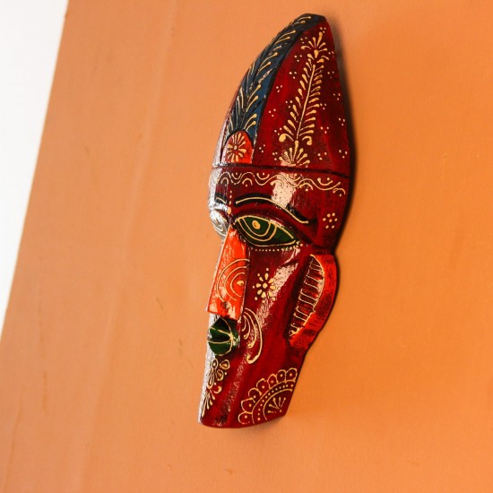 Hand Painted Tribal Face Mask – Maroon Floral Hand-carved wooden tribal face mask hand painted in deep maroon with green eyes and lips, a blue feathered crown, and fine white and orange floral motifs across the face.