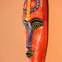 Hand Painted Tribal Face Mask – Orange Mandala Large hand-carved wooden tribal face mask hand painted in bright orange with navy and mustard accents, a dotted mandala border, and fine white floral detailing across the face.