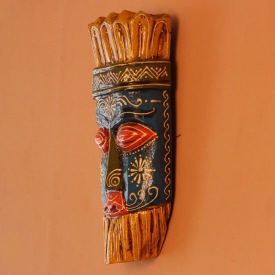 Hand Painted Tribal Face Mask – Blue & Yellow Hand-carved wooden tribal face mask hand painted in blue with red eyes and lips, a fringed mustard-yellow crown, a geometric zigzag forehead band, and white floral detailing across the face.