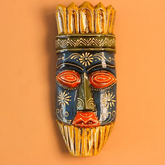 Hand Painted Tribal Face Mask – Blue & Yellow Hand-carved wooden tribal face mask hand painted in blue with red eyes and lips, a fringed mustard-yellow crown, a geometric zigzag forehead band, and white floral detailing across the face.