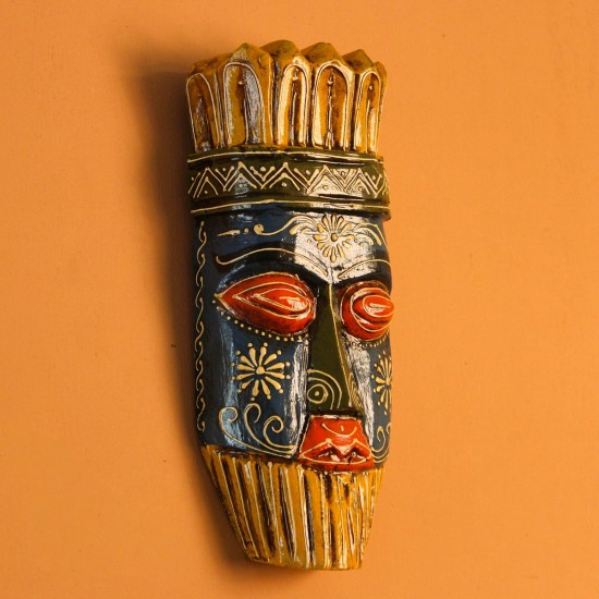 Hand Painted Tribal Face Mask – Blue & Yellow Hand-carved wooden tribal face mask hand painted in blue with red eyes and lips, a fringed mustard-yellow crown, a geometric zigzag forehead band, and white floral detailing across the face.