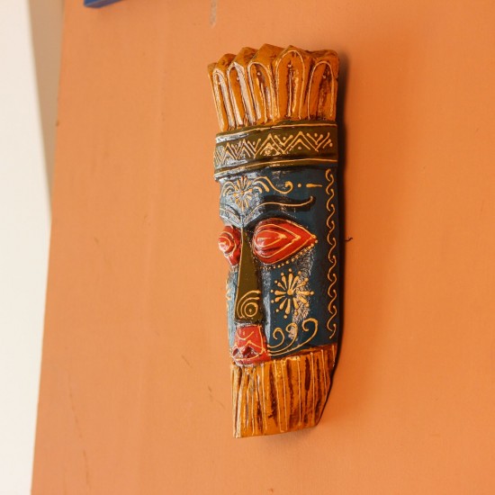 Hand Painted Tribal Face Mask – Blue & Yellow Hand-carved wooden tribal face mask hand painted in blue with red eyes and lips, a fringed mustard-yellow crown, a geometric zigzag forehead band, and white floral detailing across the face.