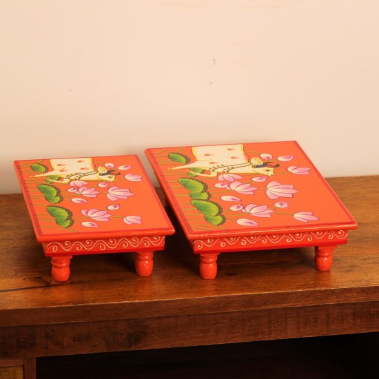 Hand Painted Cow & Lotus Chowki – Large Large wooden chowki hand painted in Pichwai style, featuring a cow standing amid blooming pink lotus flowers on a vivid red base, edged with a plain wooden border.