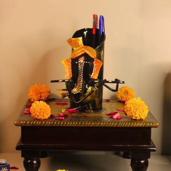 Handcrafted Ganesha metal pen stand styled with marigold flowers and festive pooja decor