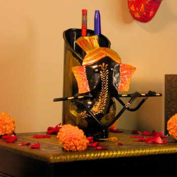 Handcrafted Ganesha metal pen stand styled with marigold flowers and festive pooja decor