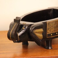 Dark Wooden Decorative Bowl Dark wooden oval bowl featuring sculpted animal-shaped ends and an ornate gold-patterned side panel.
