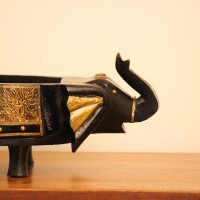 Dark Wooden Decorative Bowl Dark wooden oval bowl featuring sculpted animal-shaped ends and an ornate gold-patterned side panel.