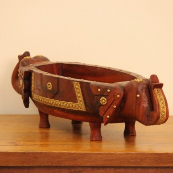 Brown polish wooden elephant head fruit bowl with brass detailing placed on a wooden table as a dining or console centrepiece.