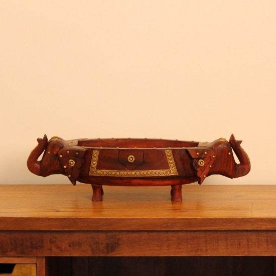 Two Elephant Head Fruit Bowl Styled on Table Brown polish wooden elephant head fruit bowl with brass detailing placed on a wooden table as a dining or console centrepiece.