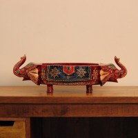 Two Elephant Head Fruit Bowl – Hand Painted Red Wooden fruit bowl flanked by two carved elephant heads with brass tusk accents, hand painted in red with a blue floral panel across the bowl's front.