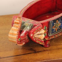 Two Elephant Head Fruit Bowl – Hand Painted Red Wooden fruit bowl flanked by two carved elephant heads with brass tusk accents, hand painted in red with a blue floral panel across the bowl's front.