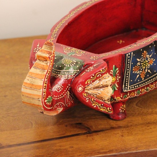 Two Elephant Head Fruit Bowl – Hand Painted Red Wooden fruit bowl flanked by two carved elephant heads with brass tusk accents, hand painted in red with a blue floral panel across the bowl's front.