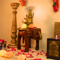 Decorative elephant brass art stool used as a pooja pedestal with an idol and flowers, adding traditional charm to a living space.