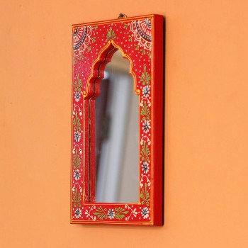 Hand-carved wooden mirror frame in a jharokha arch shape, hand painted in red with a fine floral border in blue, green, and white, framing an arched mirror at the centre.