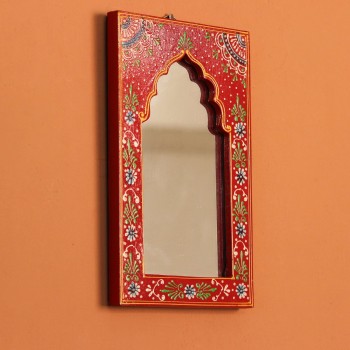 Hand-carved wooden mirror frame in a jharokha arch shape, hand painted in red with a fine floral border in blue, green, and white, framing an arched mirror at the centre.