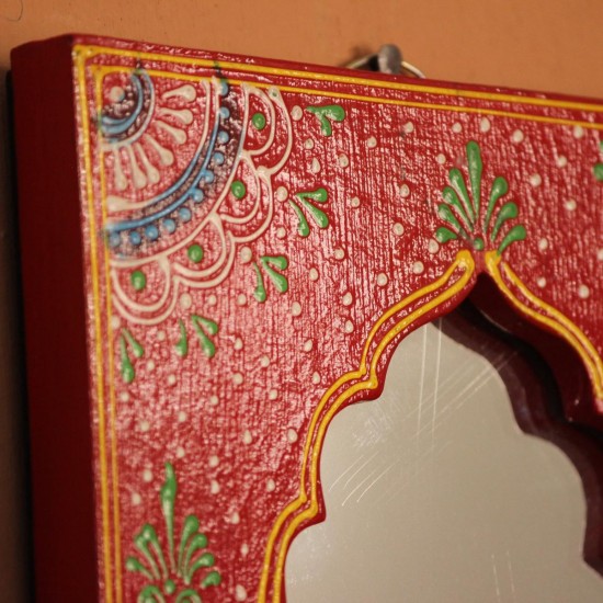 Jharokha Mirror Frame – Hand Painted Red Hand-carved wooden mirror frame in a jharokha arch shape, hand painted in red with a fine floral border in blue, green, and white, framing an arched mirror at the centre.