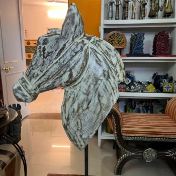 Hand-carved wooden horse head in a distressed whitewash finish, with a flowing textured mane, mounted on a slender black iron stand as a standalone decorative accent.
