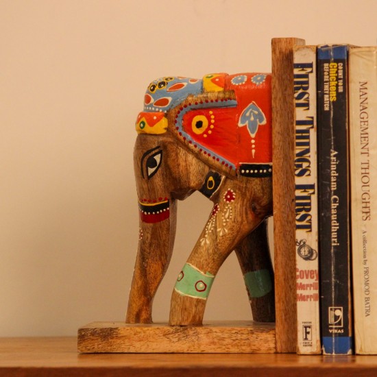 Hand Painted Wooden Elephant Bookends A pair of wooden elephant-shaped bookends, hand painted in red, blue, and yellow folk-art patterns, mounted on flat wooden bases to hold books upright.