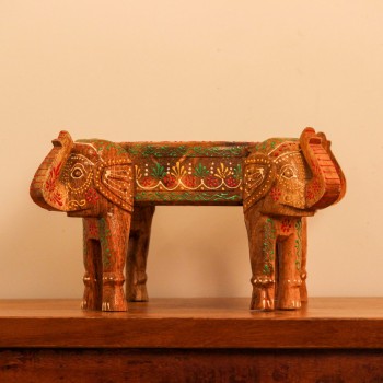 Wooden bowl held up by three carved elephant heads, hand painted in red, yellow, and green with a floral mandala pattern inside the bowl and detailed motifs on the elephants.