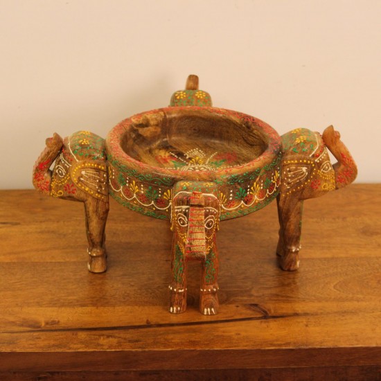 Hand Painted Wooden Elephant Bowl Stand Wooden bowl held up by three carved elephant heads, hand painted in red, yellow, and green with a floral mandala pattern inside the bowl and detailed motifs on the elephants.