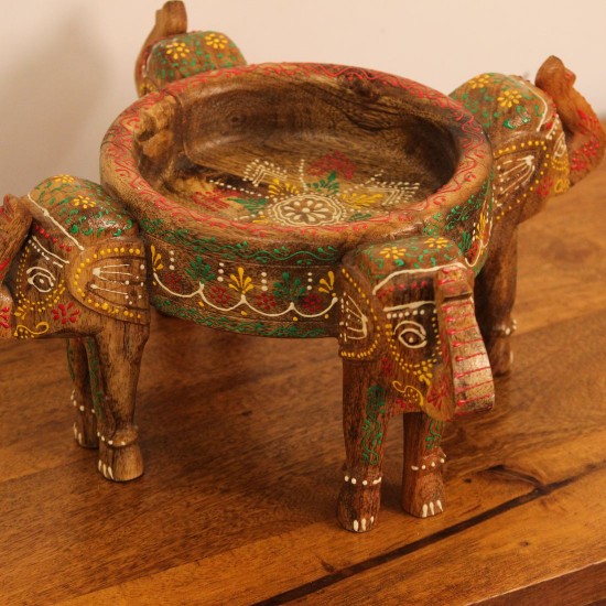 Hand Painted Wooden Elephant Bowl Stand Wooden bowl held up by three carved elephant heads, hand painted in red, yellow, and green with a floral mandala pattern inside the bowl and detailed motifs on the elephants.