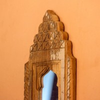 Jharokha Mirror Frame – Natural Wood, Front View Front view of a hand-carved wooden mirror frame in a jharokha arch shape, with a lattice-carved crown and an arched mirror at the centre, hung on an orange wall.