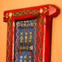 Hand Painted Blue & Red Wooden Jharokha Wall Decor Small wooden window-shaped wall decor piece hand painted in deep red frame with a blue inner panel, featuring fine traditional motifs across the surface.