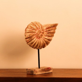 Hand-carved wooden sculpture shaped after a spiral ammonite fossil, showing ridged chamber detailing along its curve, mounted upright on a compact stand.