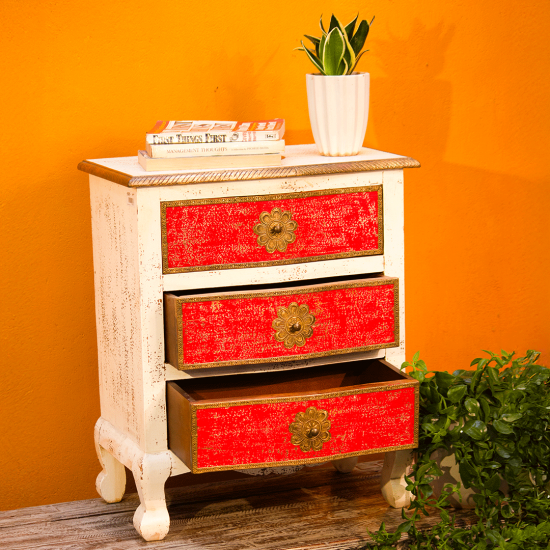 White and red wooden bedside drawer with embossed brass detailing front view White and red wooden bedside drawer with embossed brass detailing front view