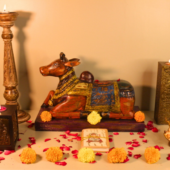 Handcrafted Wooden Nandi Idol for Pooja & Living Room Handcrafted antique multicolor Nandi wooden sculpture surrounded by marigold flowers, candles, and rustic décor accents – traditional Indian handicraft from Udaipur.