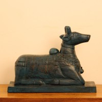 Dark teal blue carved wooden Nandi on a rectangular base placed on a wooden table as a pooja or console accent.